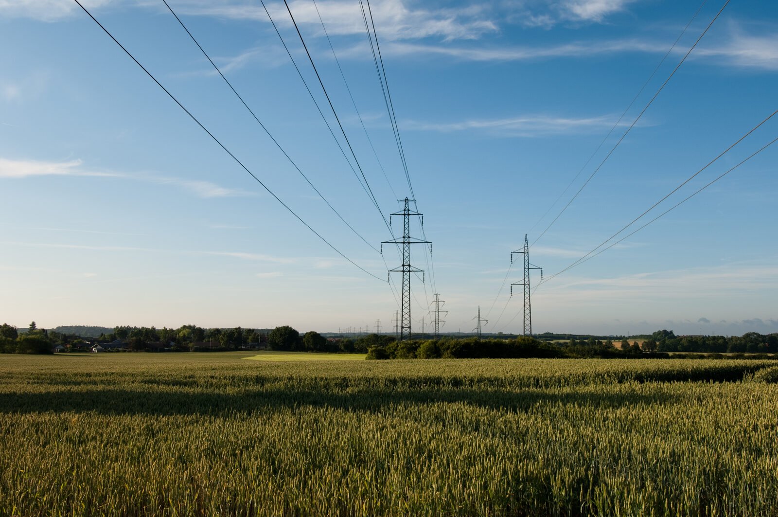 Electricity transmission lines crossing a field under a blue sky